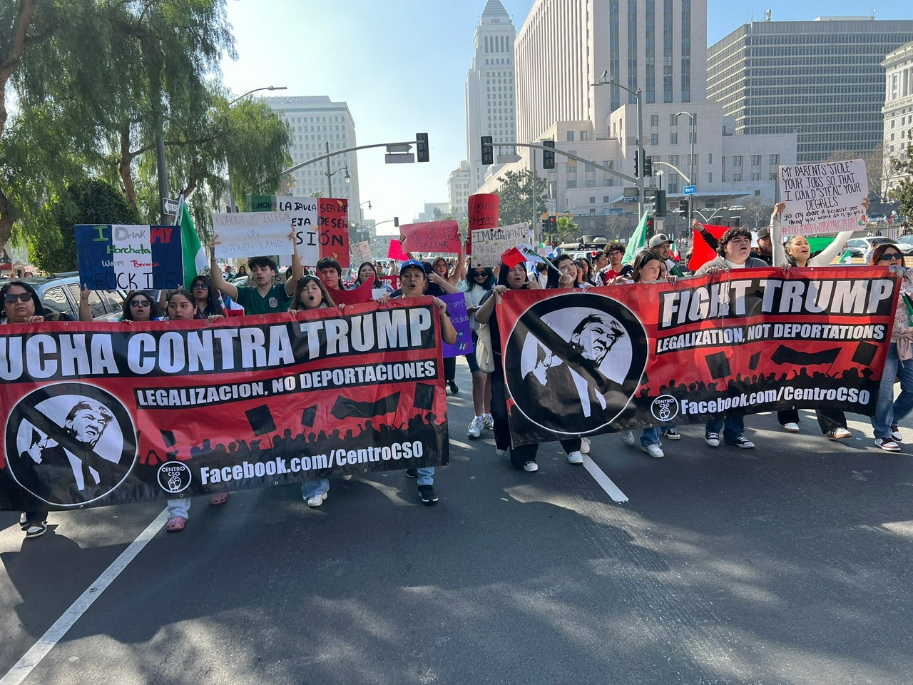 A crowd of people marches holding banners.