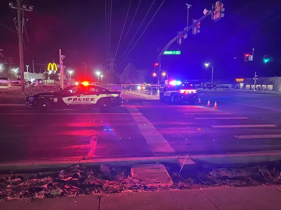 Colorado Springs police vehicles with their lights on block an intersection.