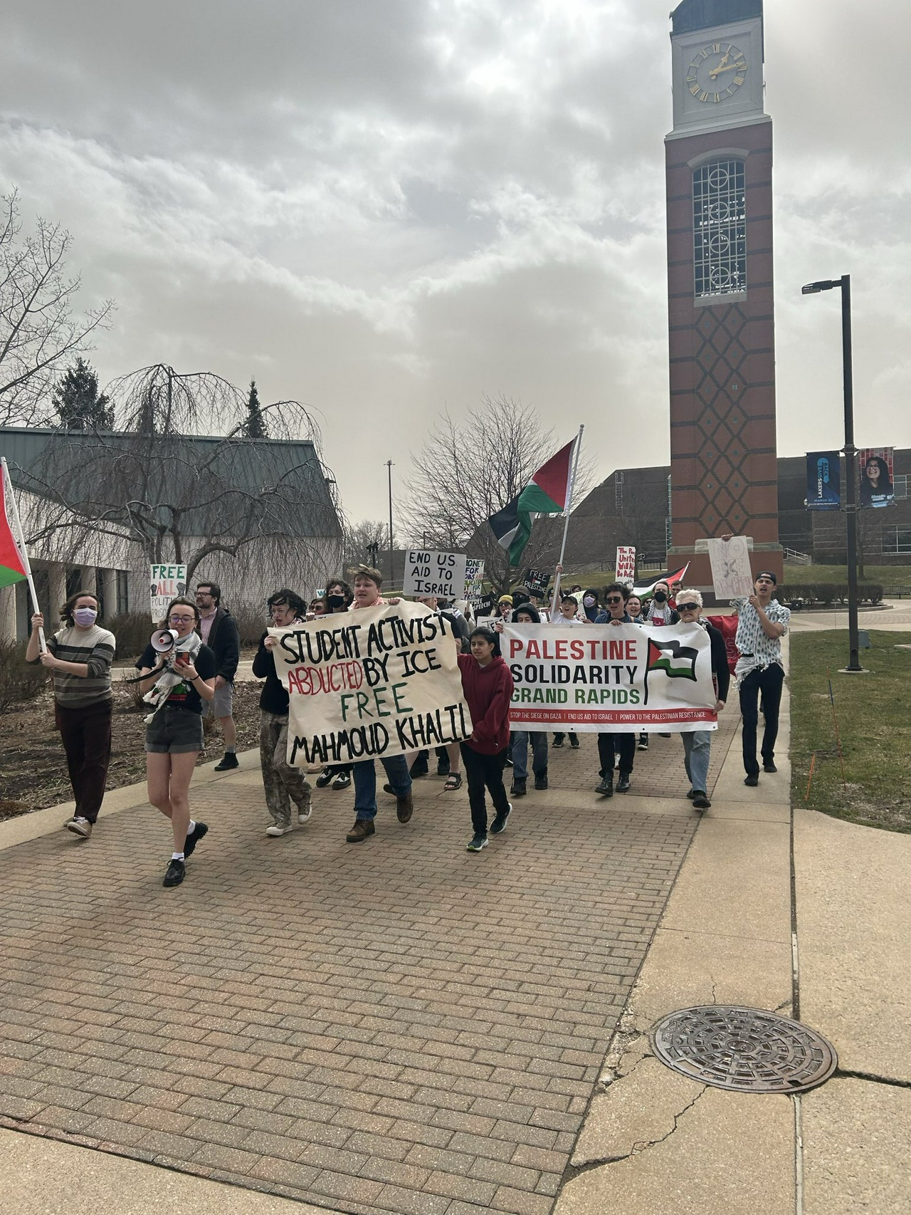 A crowd of people holding signs, megaphones, and Palestinean flags.