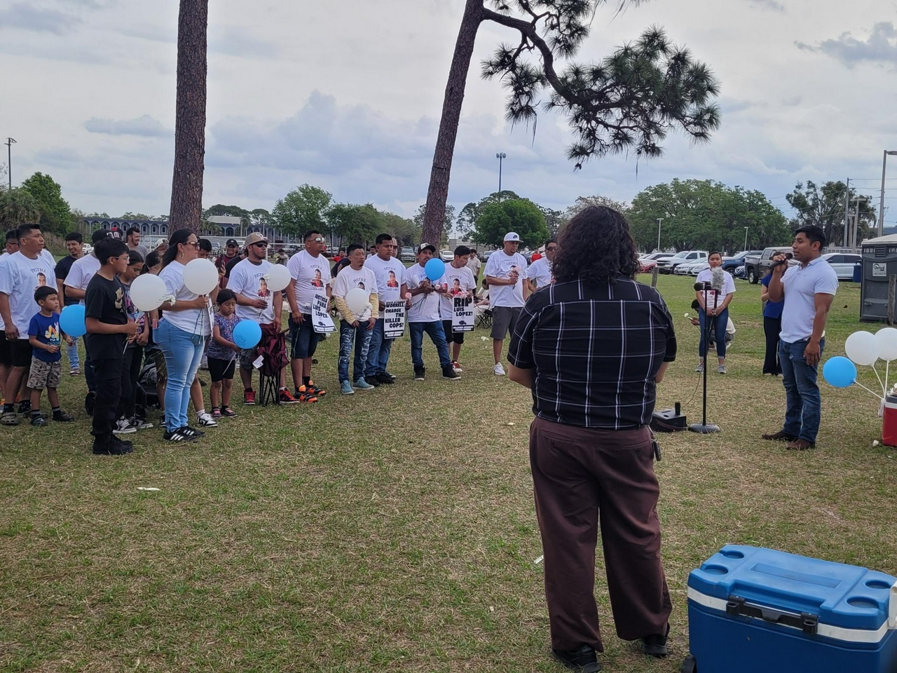 A group of people stand holding white and blue balloons 