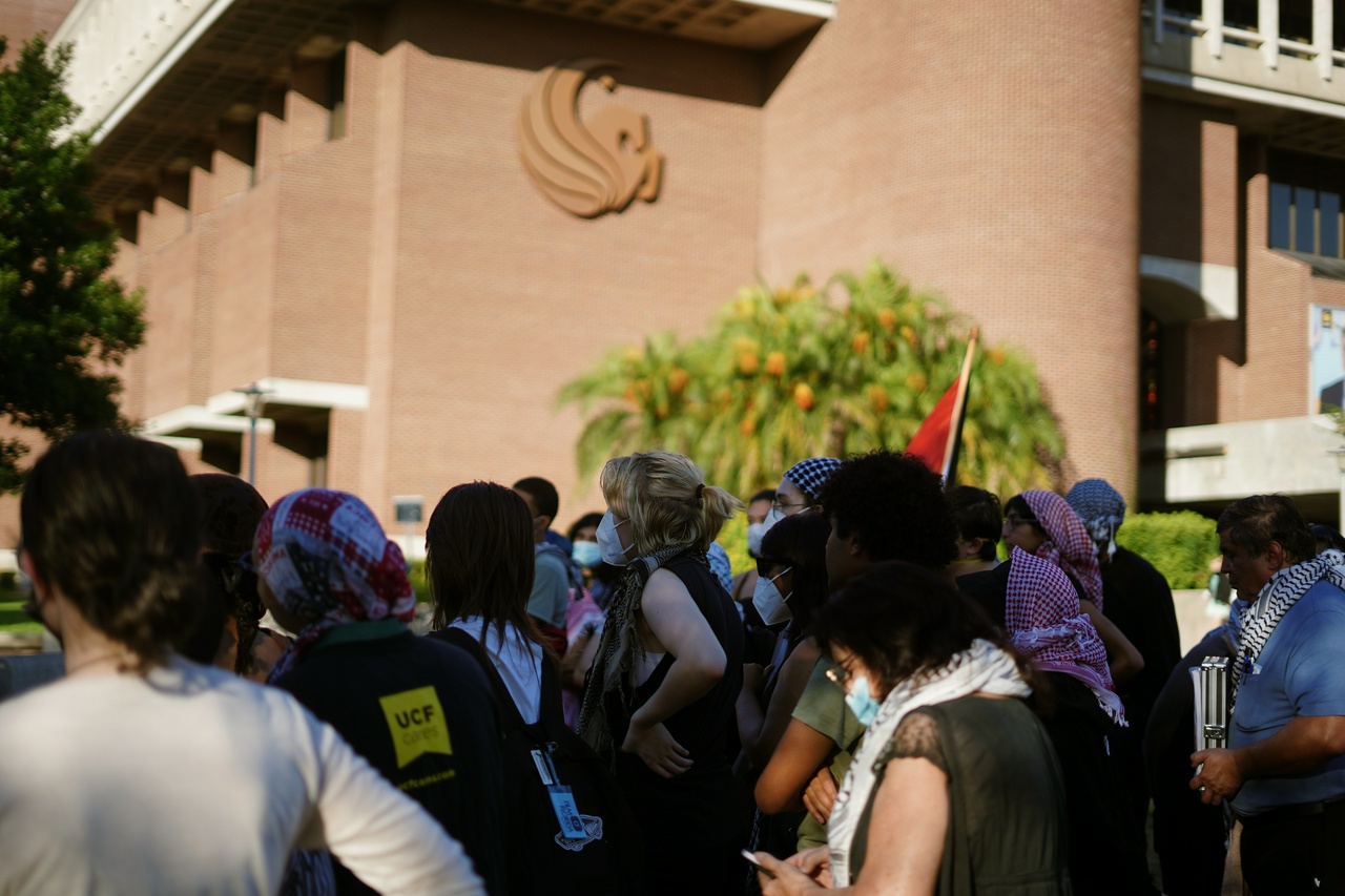 Students wearing keffiyehs and holding Palestinian flags gather.