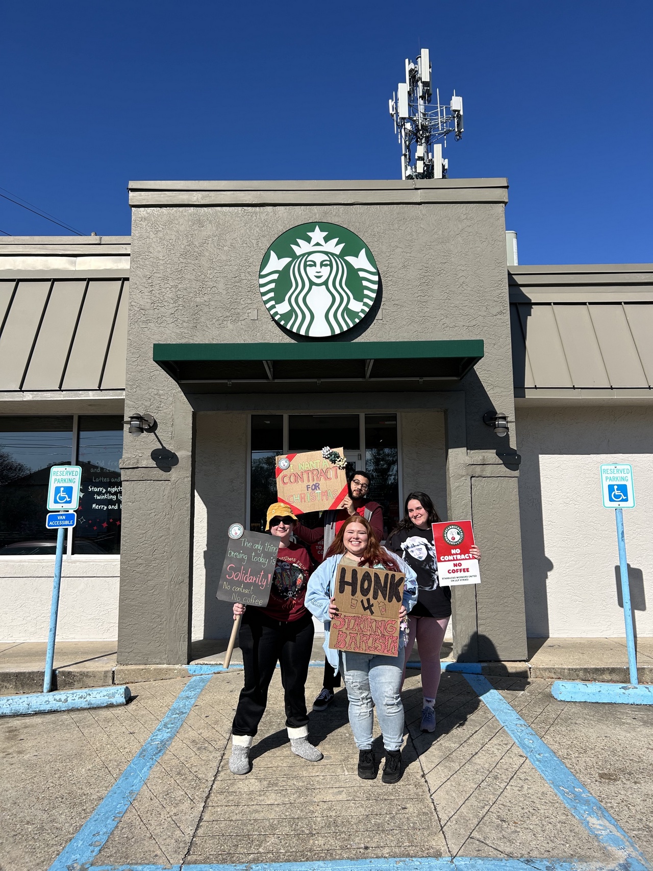 Starbucks workers wave signs in front of store.
