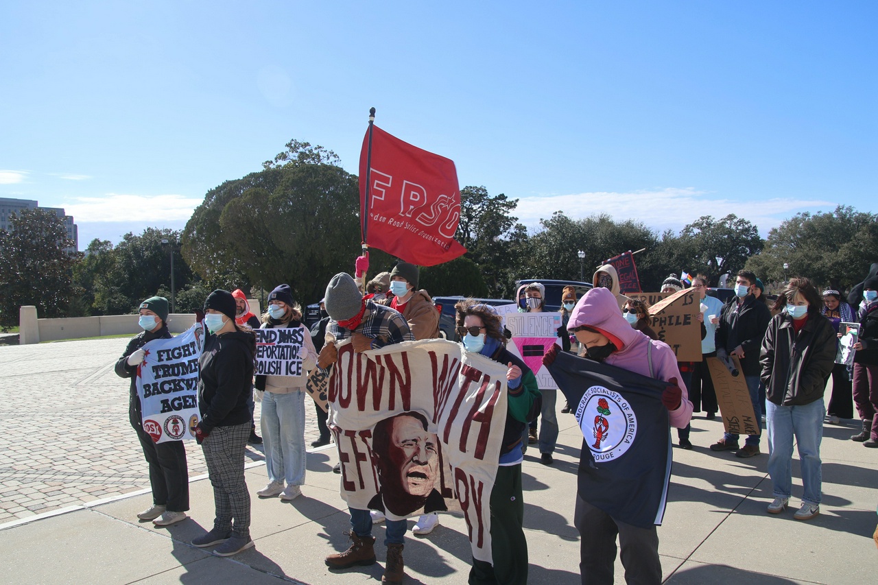 A group of protestors holding signs, banners and flags. 