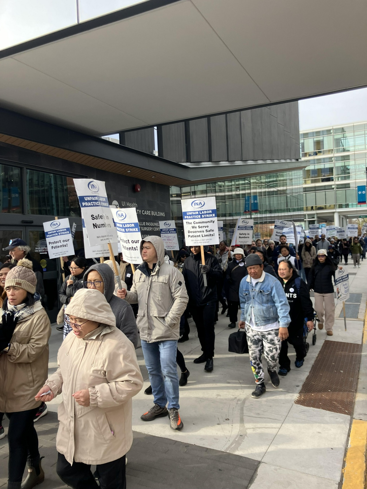 Hundreds of picketers march with signs saying things like “Protect our patients” and “The community we serve deserves safe patient limits”.