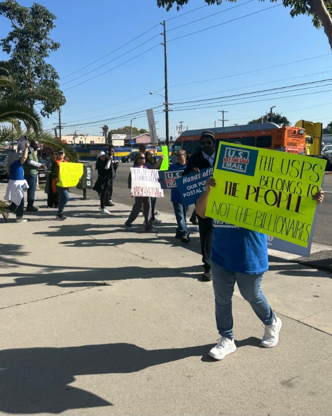 A group of people on a sidewalk holds signs.