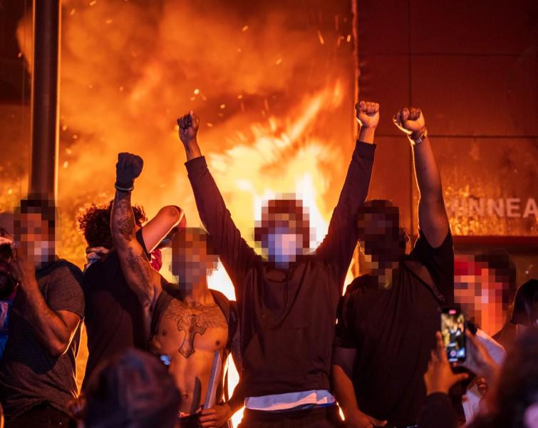People celebrate as the Minneapolis Police Dept's Third Precinct burns
