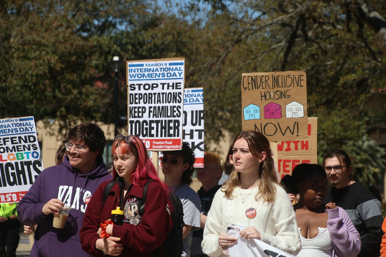 A crowd of students hold signs saying, "Defend Women's and LGBTQ Rights."