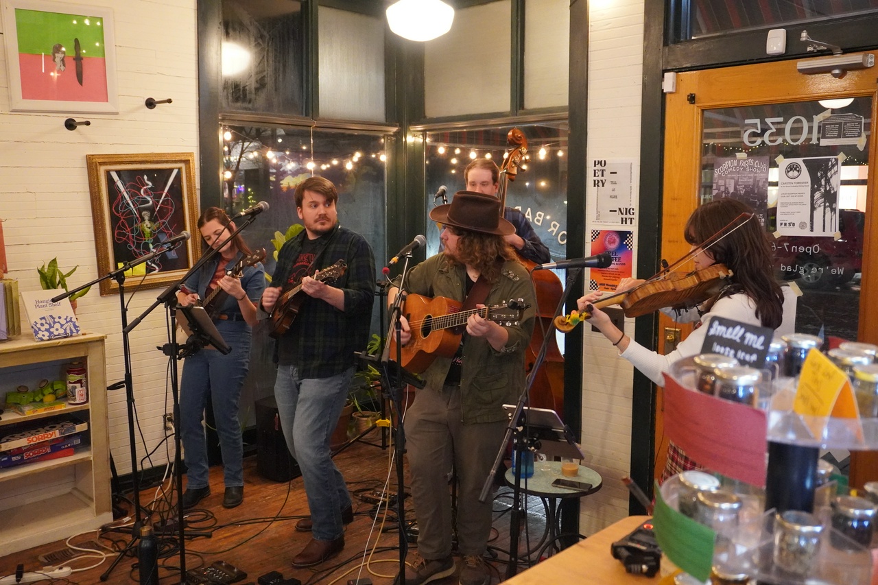 A acoustic string band quintet playing in a coffee shop.
