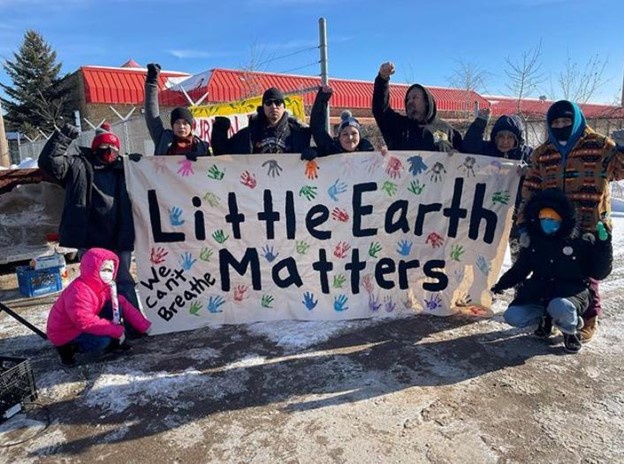 East Phillips residents hold a banner that youth in Little Earth painted.