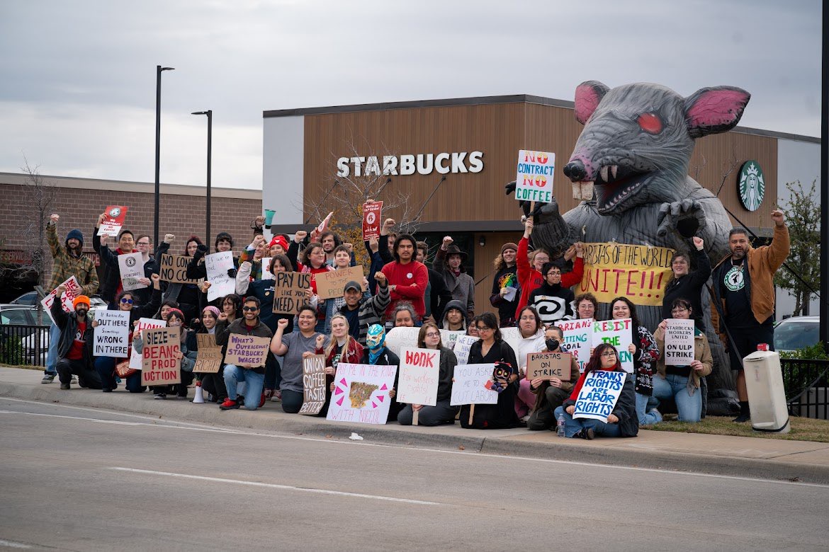 Starbucks workers on strike outside a Starbucks store with a giant inflatable rat.