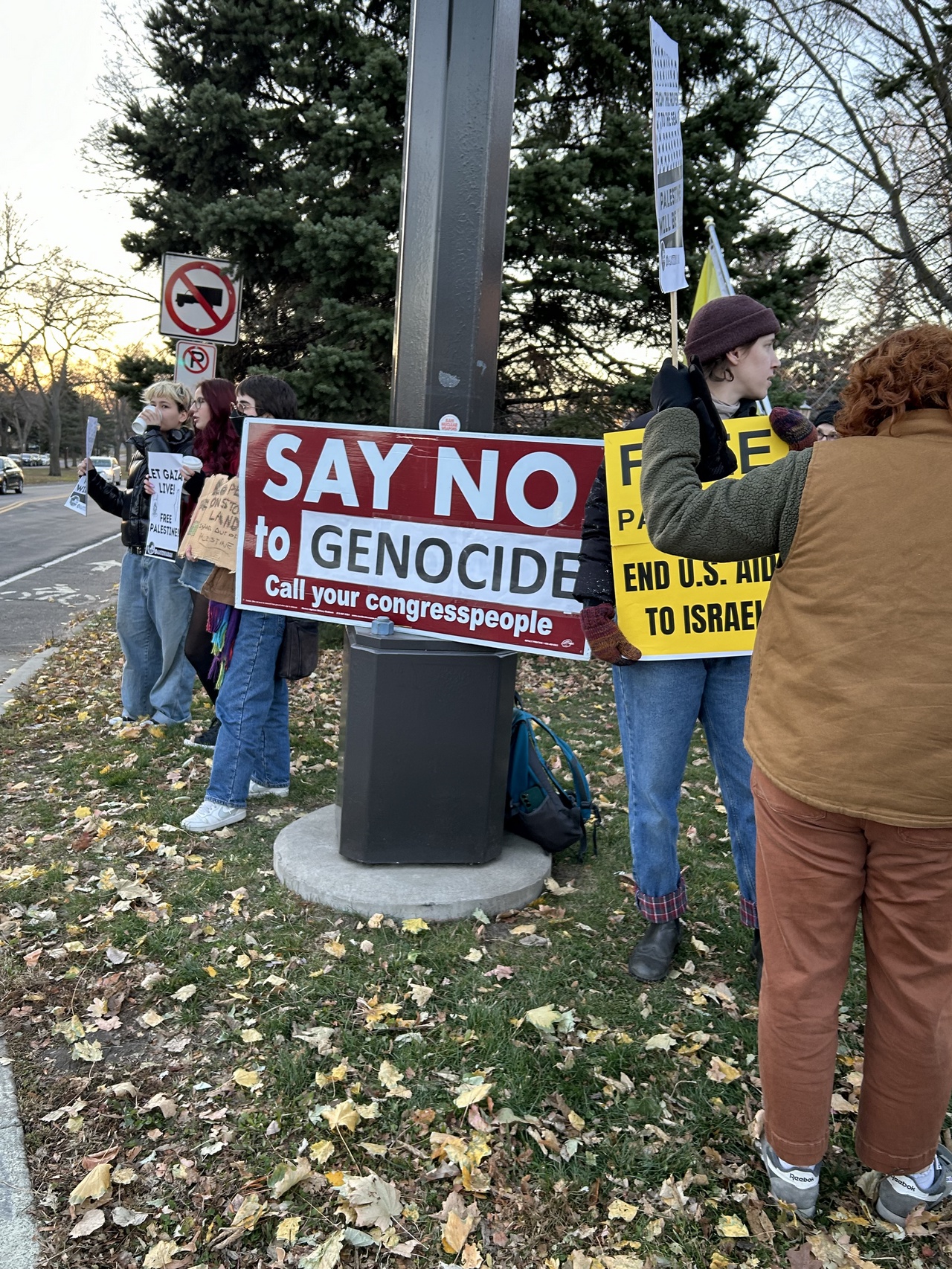 Protestors hold signs that say slogans like "Let Gaza Live" and "Say No To Genocide".