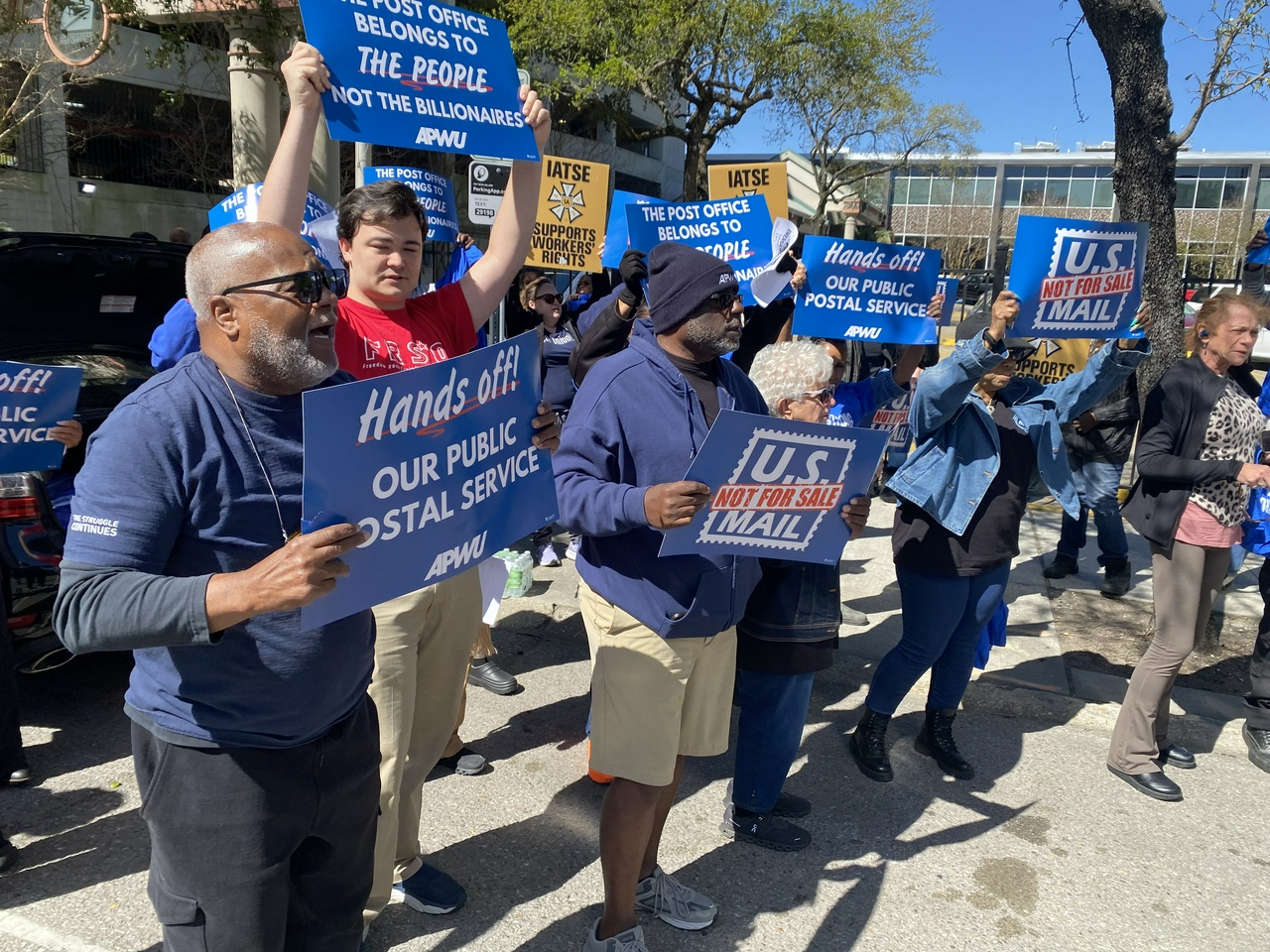 A group of people stand holding signs.