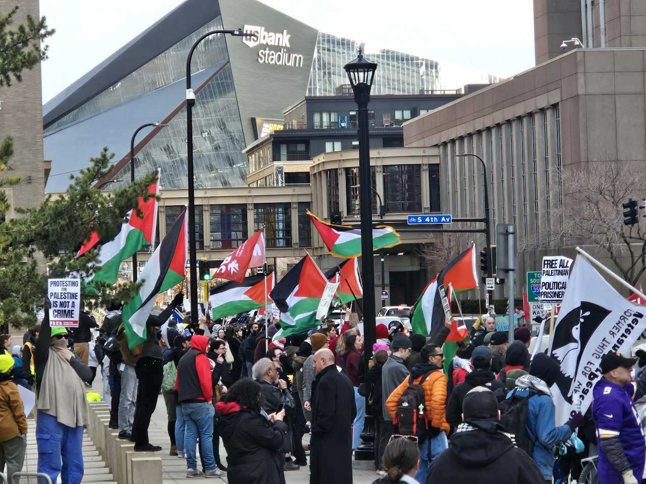 A group of protesters holding Palestinian flags and signs.