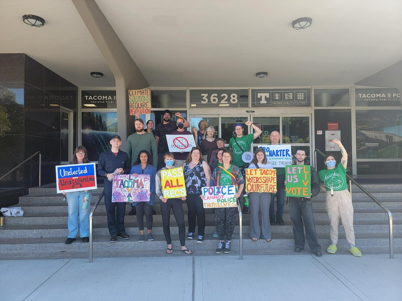 Tacoma activists hold signs in front of City Hall that push for progressive changes to the city charter.