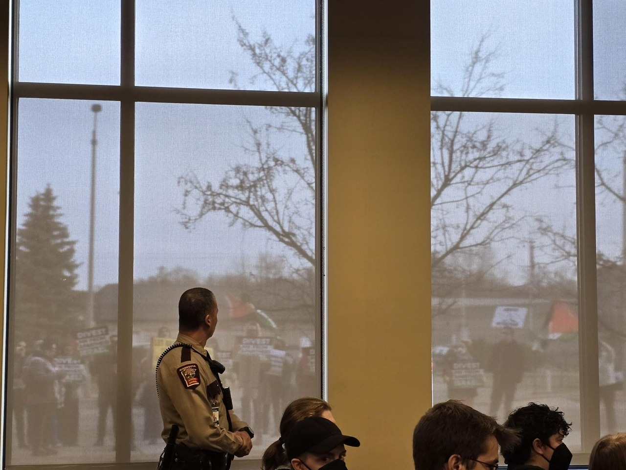 A Minnesota State Trooper watches as dozens of advocates for divestment from Israel protest outside the at-capacity SBI meeting room.