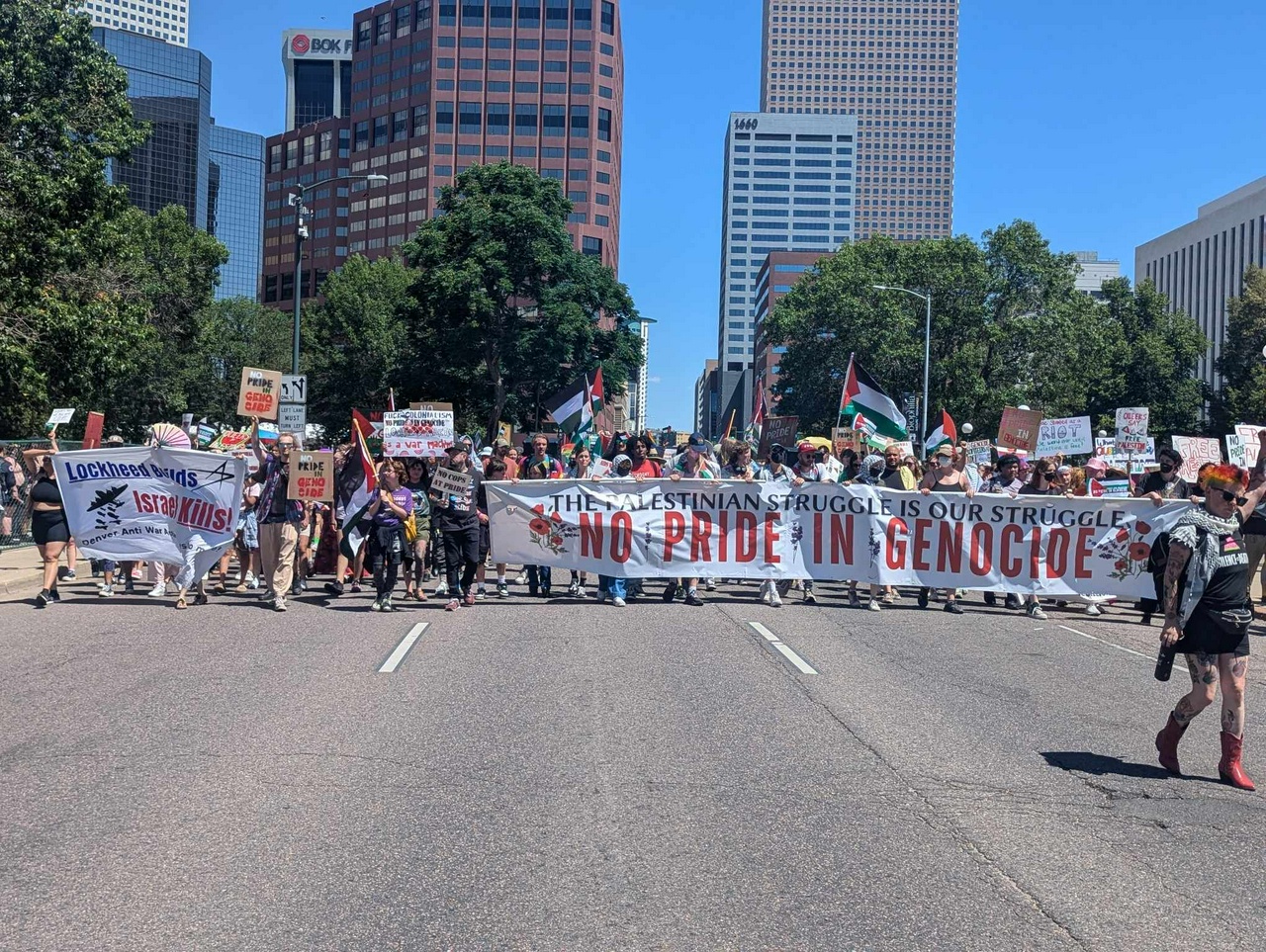 Hundreds of Pro-Palestine protestors march in the street holding signs and banners.