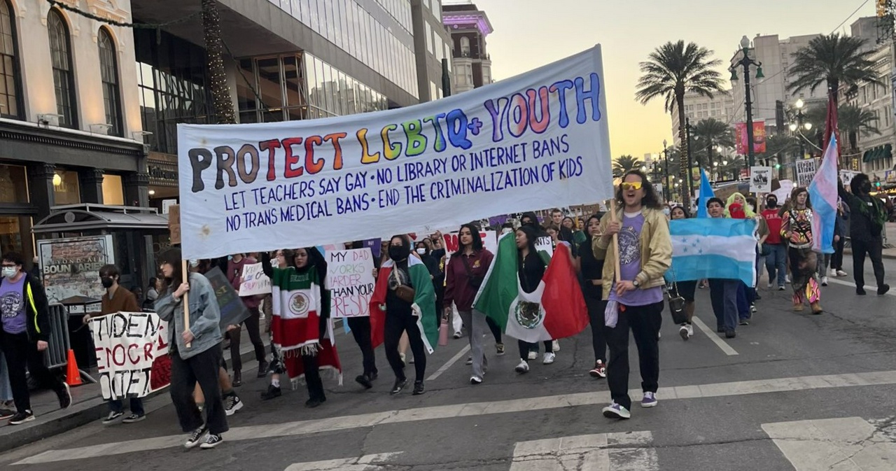 Anti Trump protesters carry flags and a banner on Canal Street in New Orleans.