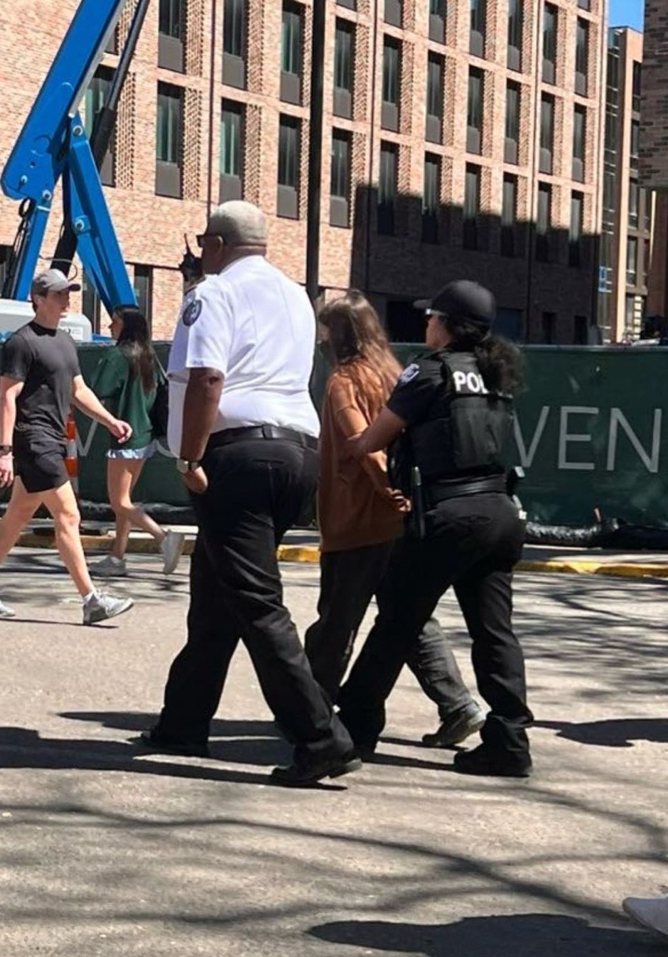 Two police officers arrest a student.