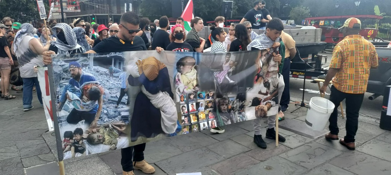 Pro-Palestine protesters hold Nakba banner displaying Palestinian victims of Israeli attacks.