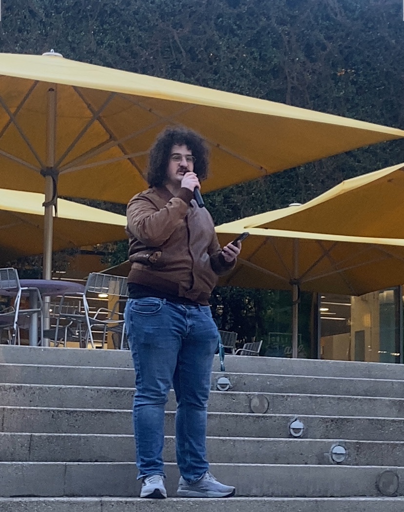 Speaker holds microphone to mouth while standing on steps.
