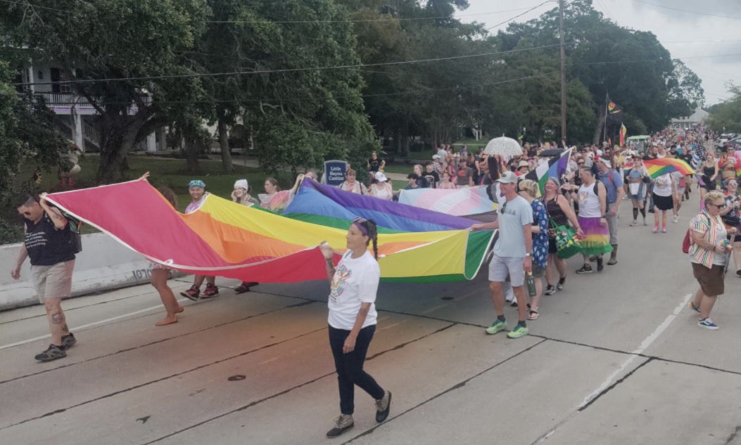 Mandeville residents carry a giant Pride flag across the street.  | Fight Back! News/Naomi Retherford