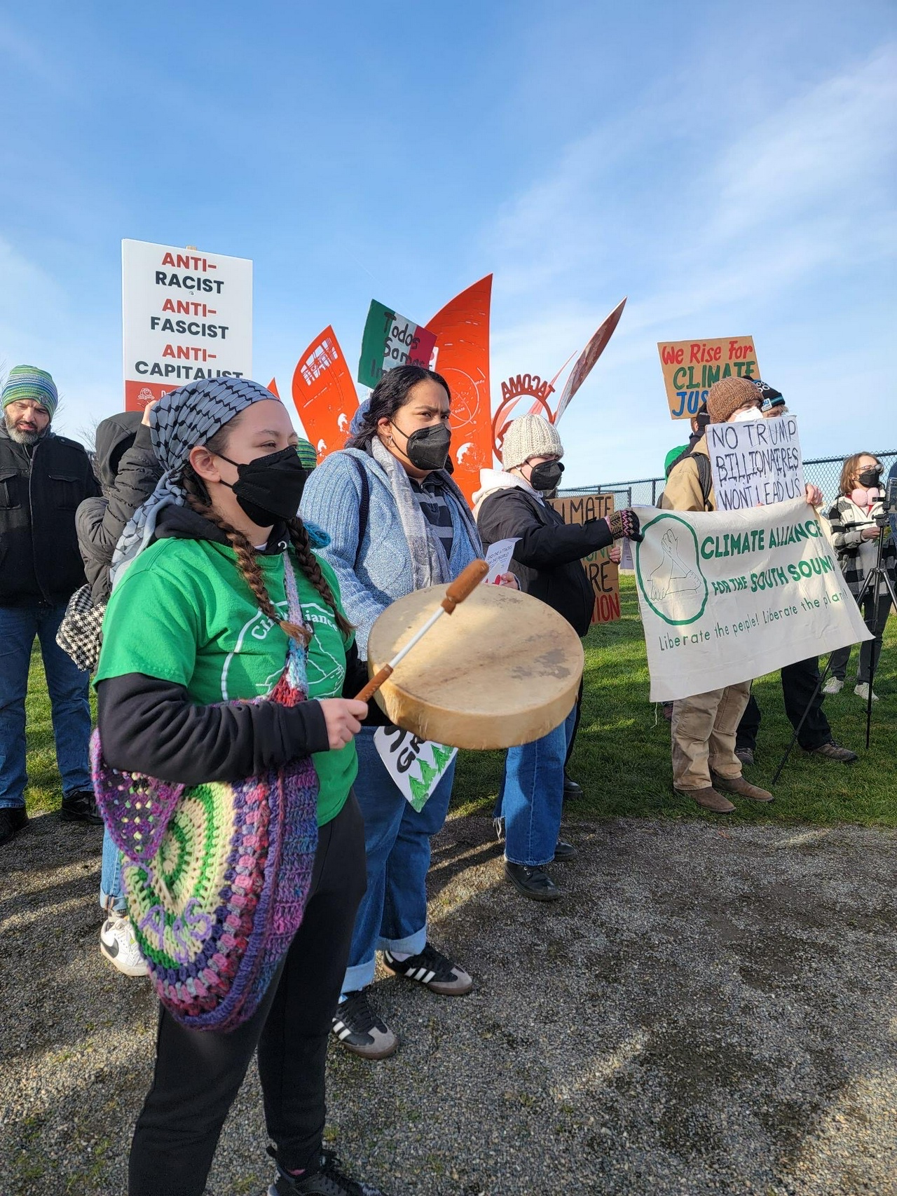 Protestors wearing KN95 masks hold signs and banners that read slogans like “No Trump, Billionaires won’t lead us” and “We rise for climate justice”.