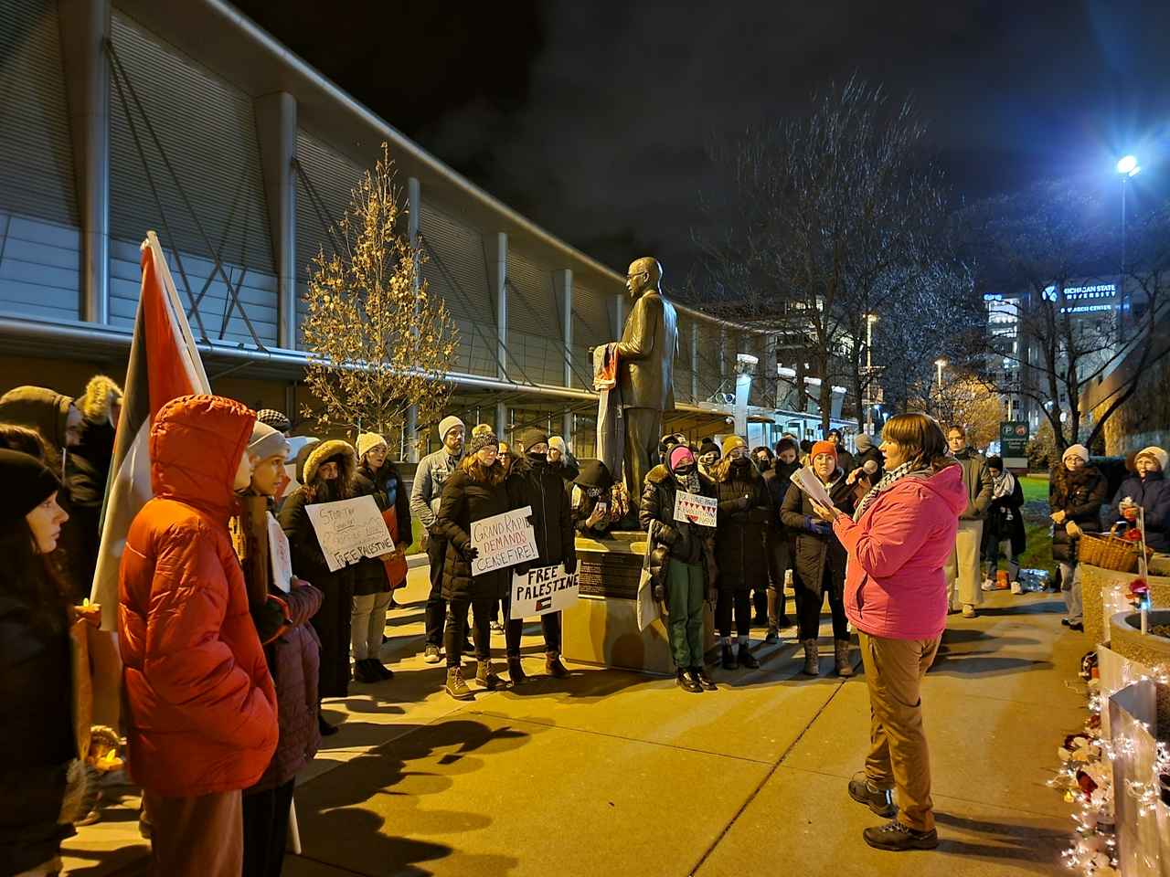 Group of protesters gather around a speaker talking on a mic.