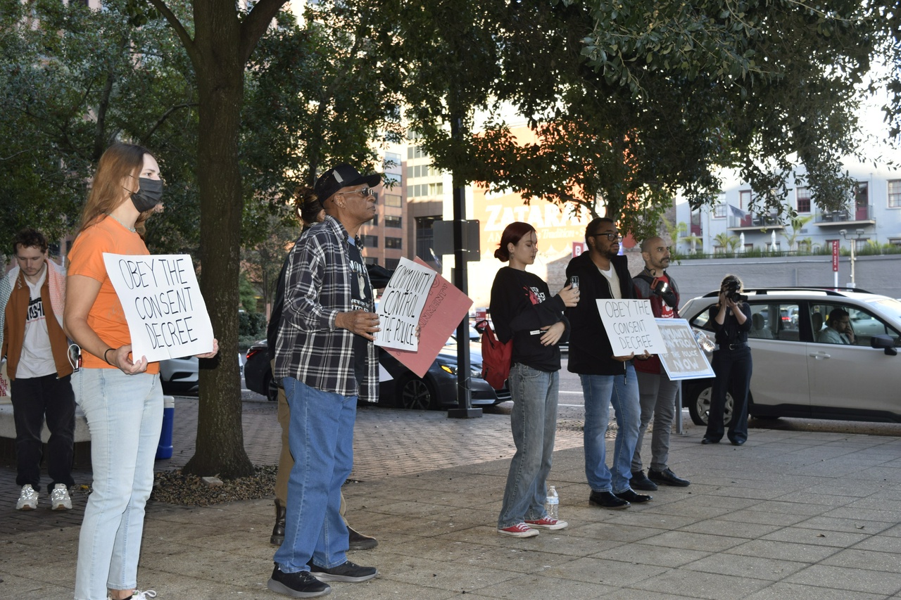 Protesters holding signs on a sidewalk.