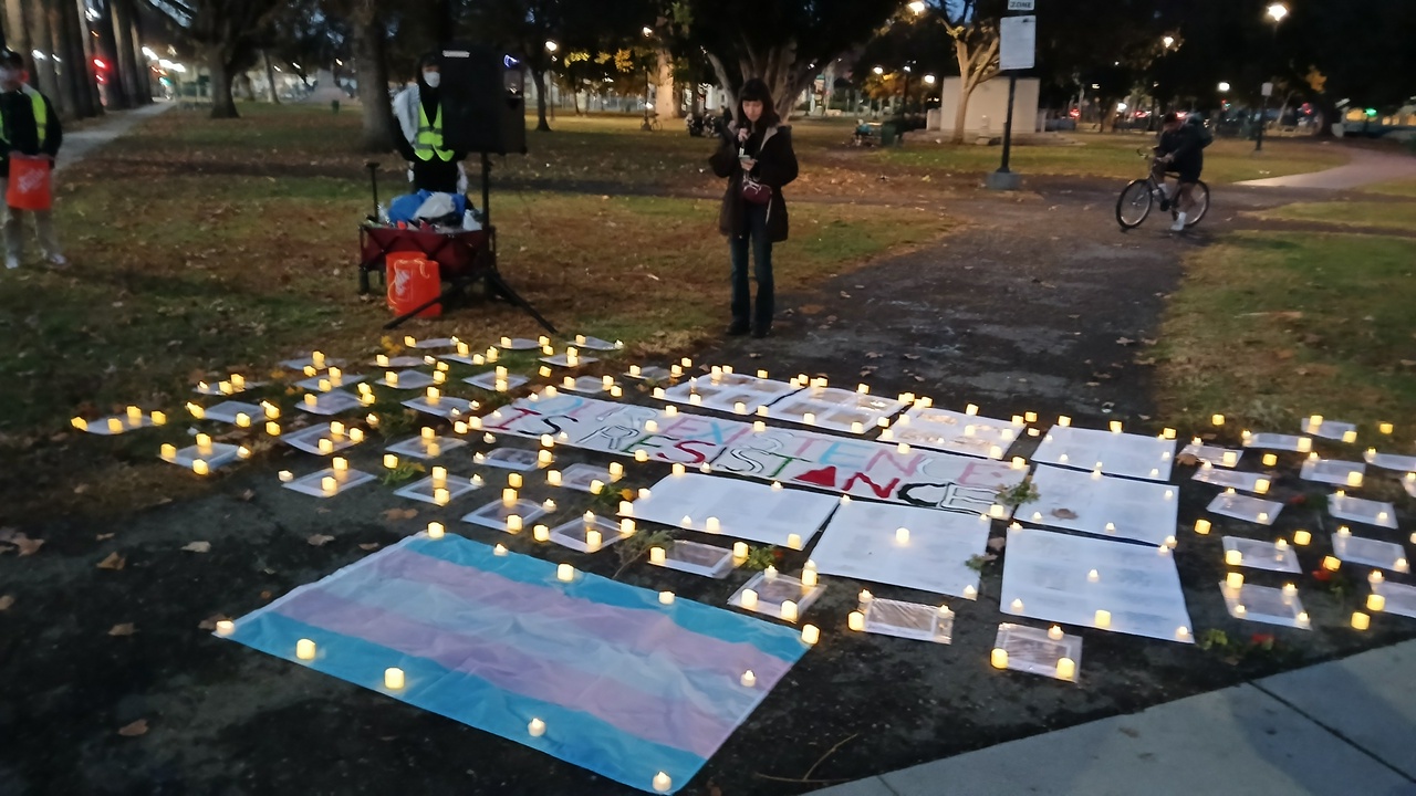 A vigil with portraits on the ground with candles around them.