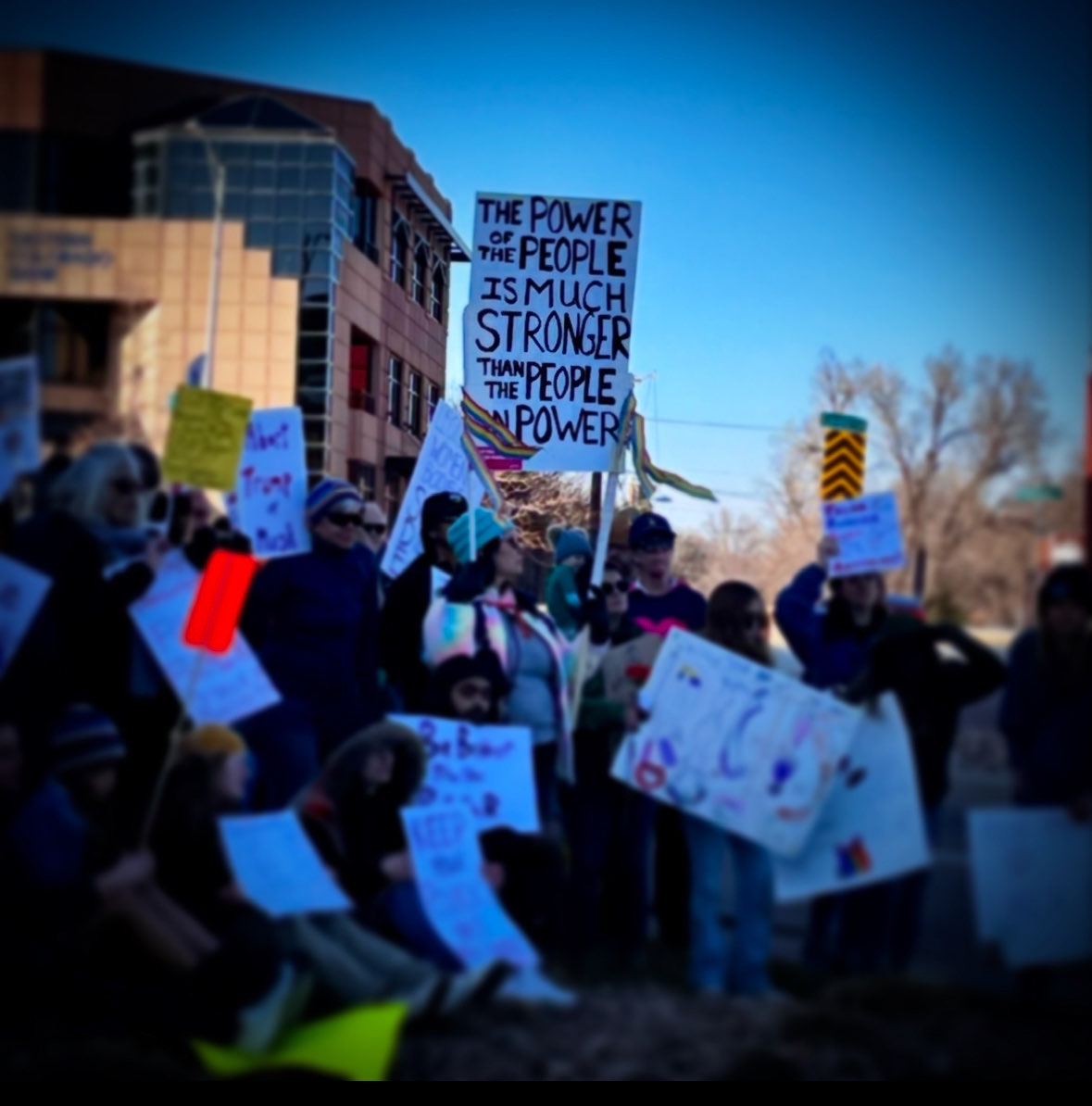 Protesters carry signs with slogans like “The power of the people is much stronger than the people in power”