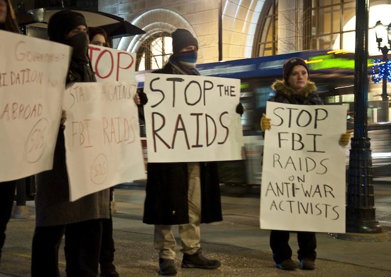 Protestors holding signs against FBI raids on antiwar movement