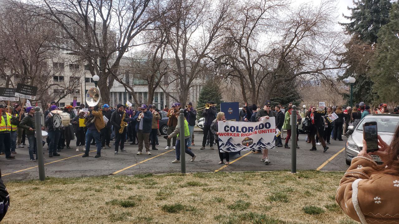 A crowd of people holding signs, banners, and musical instruments.