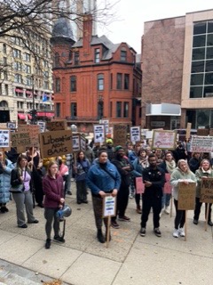Crowd gathers holding signs.