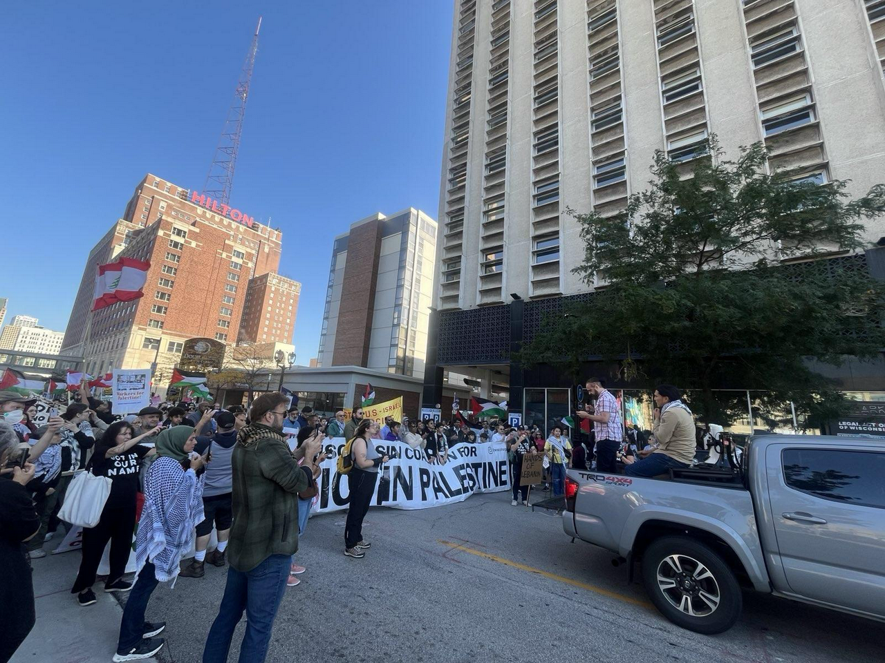 Marchers carry signs and Palestinian and Lebanese flags behind banner that reads “Wisconsin Coalition for Justice in Palestine”