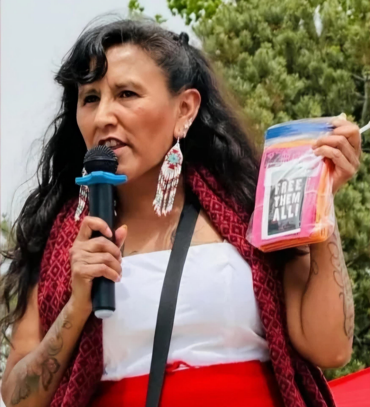 A woman, Jeanette Vizguerra, gives speech and holds up flyers that say, "Free 极速赛车一分钟计划 168极速赛车专家预测 Them All!"